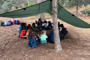 Alumnes de 3r de primària en una sessió d'escola bosc de Claver Natura en un dia de pluja