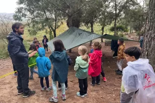 Alumnes de 3r de primària en una sessió d'escola bosc de Claver Natura en un dia de pluja